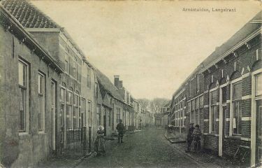 De Langstraat met aan de linker kant het doktershuis met de twee dakkapellen. Het eerste huis links is van timmermansbaas Jan Buis met daar tegenover zijn werkplaats. De Langstraat met aan de linker kant het doktershuis met de twee dakkapellen. Het eerste huis links is van timmermansbaas Jan Buis met daar tegenover zijn werkplaats.
