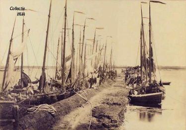 De aanleg van de Sloedam. Hierlangs leggen de vissersschuiten voorlopig aan. De aanleg van de Sloedam. Hierlangs leggen de vissersschuiten voorlopig aan.