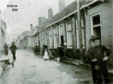 In de Westdijkstraat zien we de vrouwen druk bezig met de stoepen te schuren. Het schuren van de straten wordt dit jaar verboden. In de Westdijkstraat zien we de vrouwen druk bezig met de stoepen te schuren. Het schuren van de straten wordt dit jaar verboden.